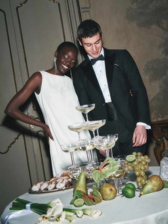 Elegantes Duo aus schlichtem, weißem ärmellosem Kleid mit klarem Schnitt und klassischem schwarzen Smoking mit Fliege und weißem Hemd.